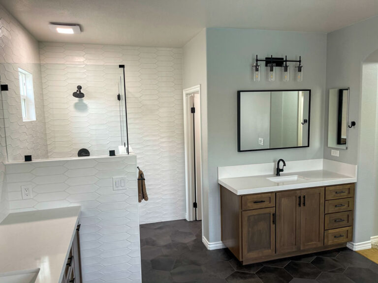 This modern bathroom features a double vanity with two sinks and a spacious walk-in shower with a glass door. The clean lines and neutral tones give the bathroom a sleek and stylish look. The two sinks and spacious countertop provide ample room for two people to get ready at the same time. The walk-in shower with a glass door creates a sense of openness and makes the bathroom feel larger. This type of bathroom would be ideal for a master bathroom or a guest bathroom.