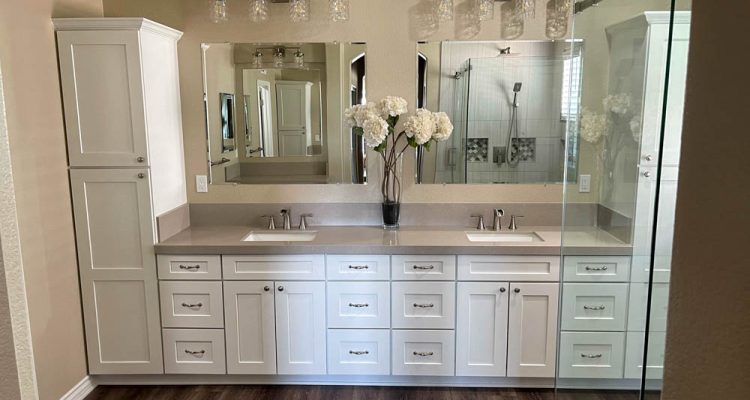 This modern bathroom sanctuary boasts a double vanity with sleek vessel sinks atop a beautiful quartz countertop. The polished chrome faucets add a touch of shine, while the white cabinets create a sense of calmness in the space. Wall-mounted light fixtures provide ample task lighting, while the large mirror reflects natural light, making the room feel even more spacious.